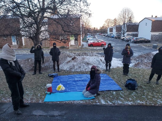 Seven protestors dressed warmly on snowy grass of a front lawn where the eviction protest took place
